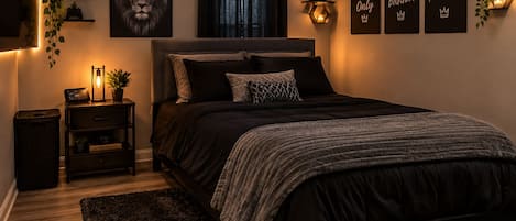 A bedroom with a bed, bedside tables, a wall-mounted TV, and motivational posters.