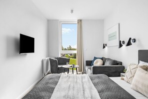 A modern hotel room with a bed, a seating area with a table, a television, and a window with a view of the outdoors. - Modern apartment with exceptional sea view and balcony at Marina Wendtorf (Wendtorf)