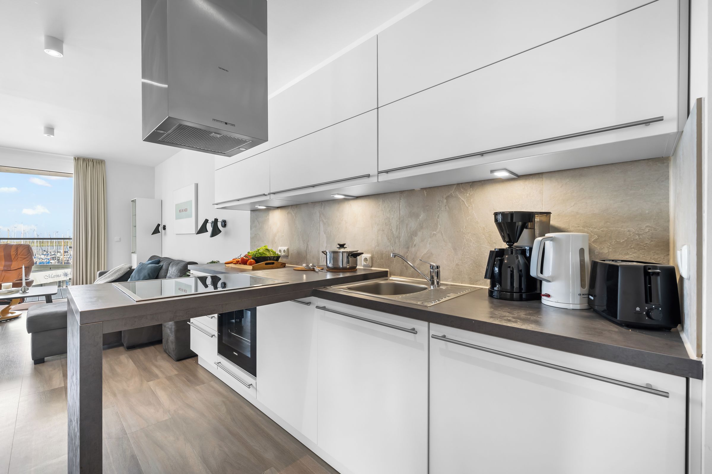A modern kitchen with a central island, stainless steel appliances, and a view of the city.