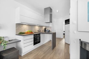 Eine moderne Küche mit weißen Schränken, einem eingebauten Backofen und einer zentralen Kochinsel mit Spüle.