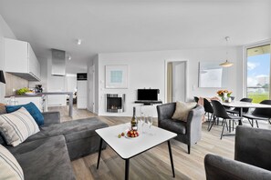 A modern living space with a dining area, kitchen, and a fireplace. - Modern apartment with exceptional sea view and balcony at Marina Wendtorf (Wendtorf)