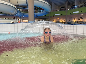 Eine Person im Pool unter einer Wasserrutsche.