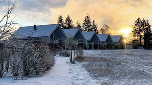 A row of cabins with a snow-covered path leading to them. - Newly Built Vacation Home "Wiesengeflüster W1" | With Garden, Indoor Sauna, and Fireplace (Röbel)