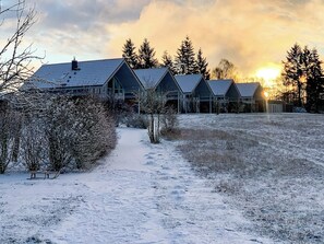 A row of cabins with a snow-covered path leading to them. - Modern Vacation Home "Wiesengeflüster W2" | New Construction in 2026 on Lake Müritz (Röbel)