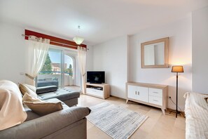 Ein modernes Wohnzimmer mit Sofa, TV-Möbel und Stehlampe.