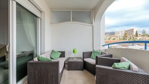 Ein Balkon mit Korbmöbeln, einer grünen Lampe und Blick auf Gebäude.