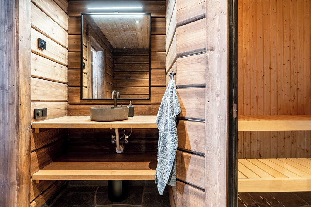 A wooden sauna with a sink, a towel, and a mirror.