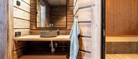 A wooden sauna with a sink, a towel, and a mirror.