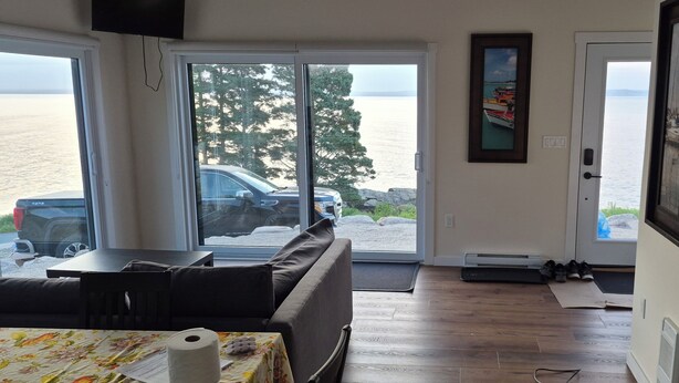 A room with a sofa, a table with a floral tablecloth, a door leading outside, and a framed picture on the wall.