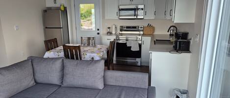 A compact kitchen with a dining area, including a sofa, table, chairs, and modern appliances.