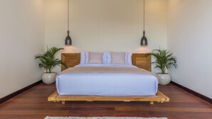 A bedroom with a wooden bed frame, two pendant lights, and potted plants. - Villa Sereine Seminyak (Seminyak)