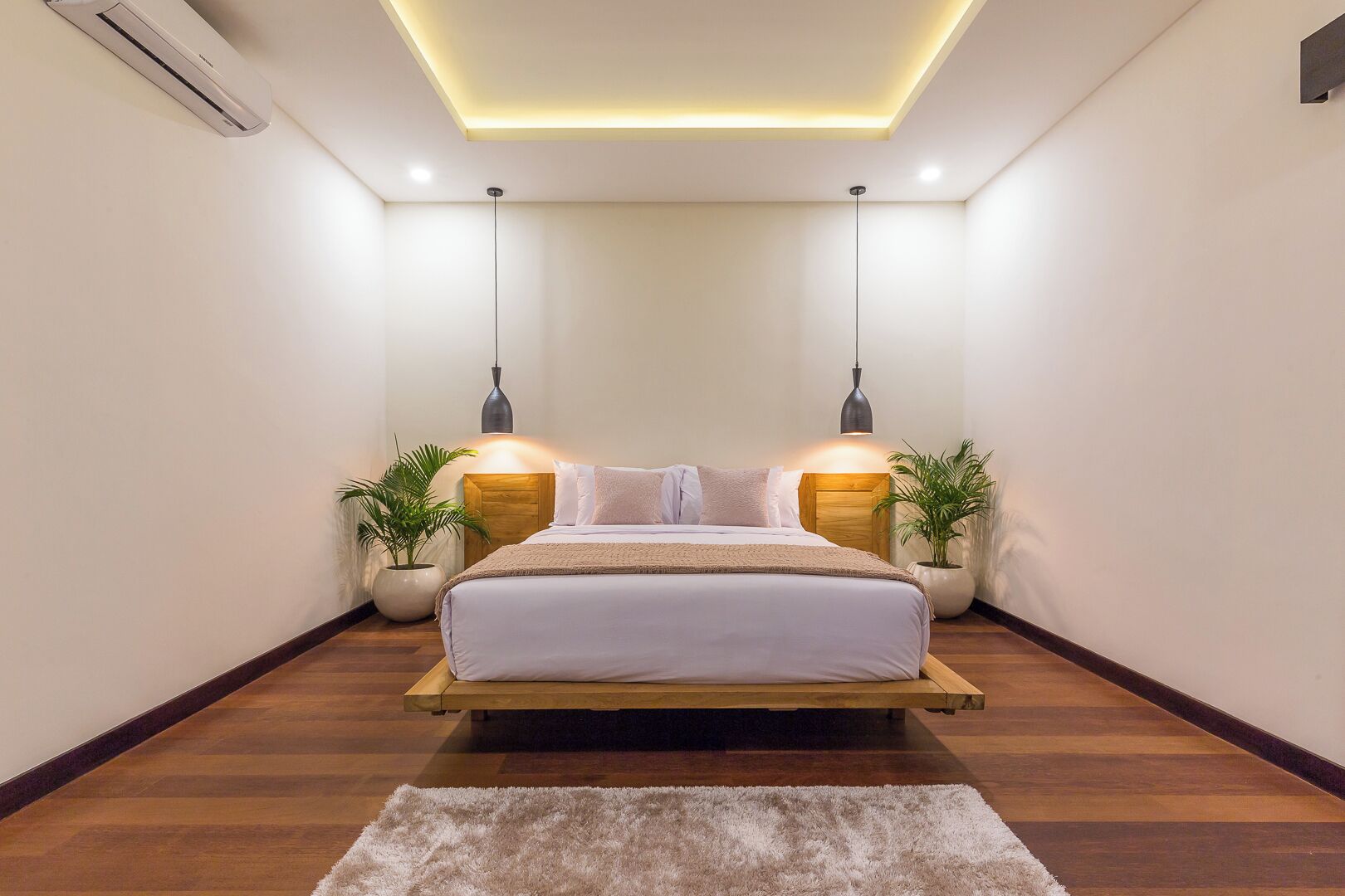 A bedroom with a bed, bedside tables, two pendant lights, and a floor lamp.