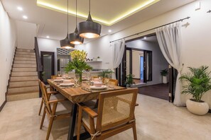 A dining area with a wooden table set for four, surrounded by wicker chairs. - Villa Sereine Seminyak (Seminyak)