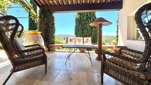 Eine Terrasse mit Korbmöbeln, einem Tisch und Blick auf die Landschaft.