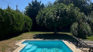A rectangular swimming pool with clear blue water, surrounded by a stone deck and a grassy area with trees. - A peaceful retreat - pool - 3 min from Lourmarin (Puyvert)
