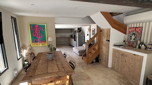 A spacious kitchen with a wooden dining table, a staircase, and a view into the living area. - A peaceful retreat - pool - 3 min from Lourmarin (Puyvert)