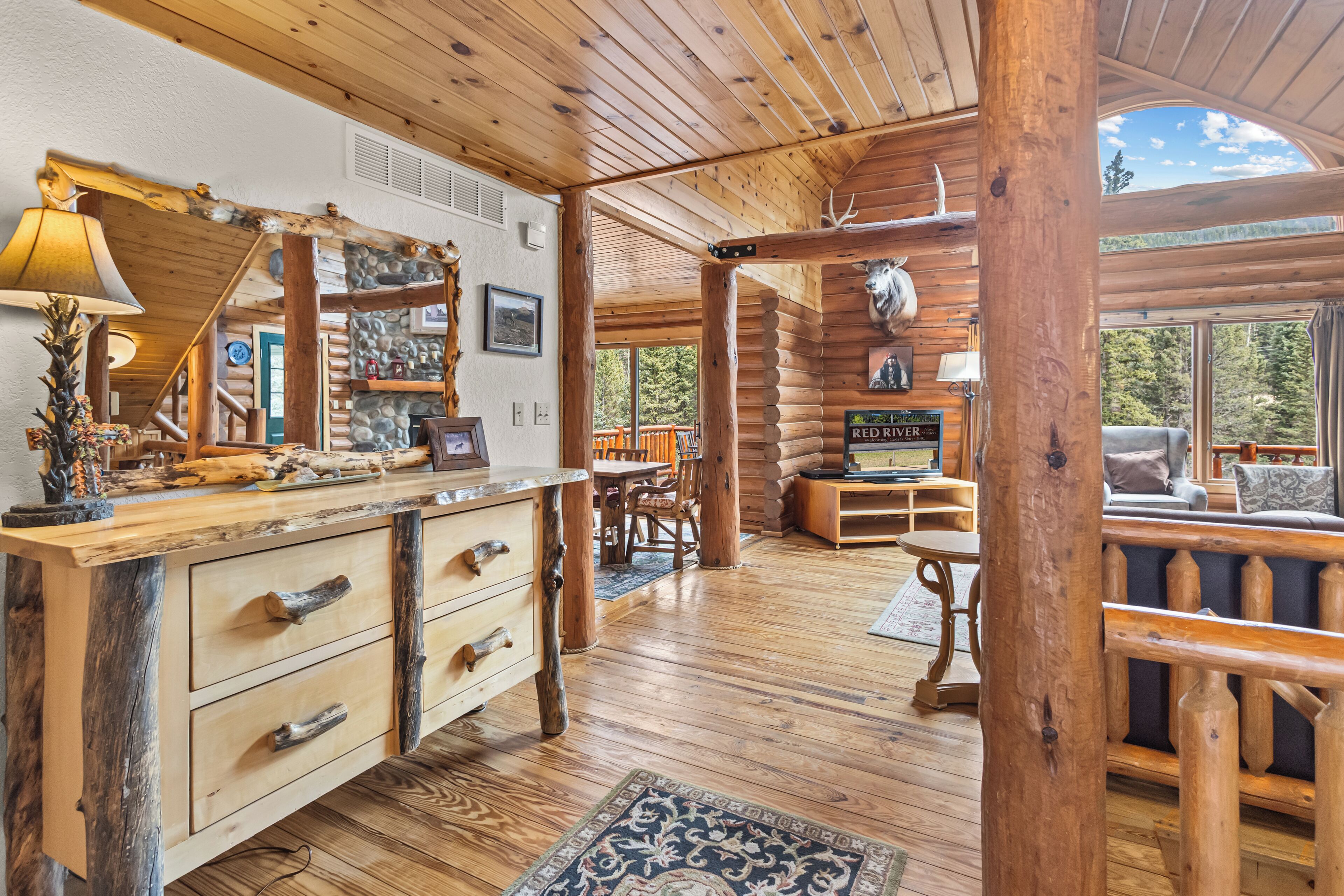 Een landelijk houten interieur met houten wanden, een stenen openhaard en een eethoek.