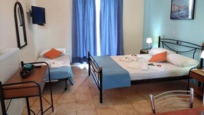 Een slaapkamer met een bed, een bureau, een stoel, een televisie en een raam met gordijnen.