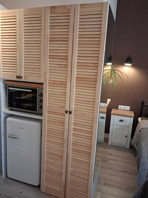 Eine kompakte Küche mit Einbauofen, Mini-Kühlschrank und Holzschränken mit Klappläden.