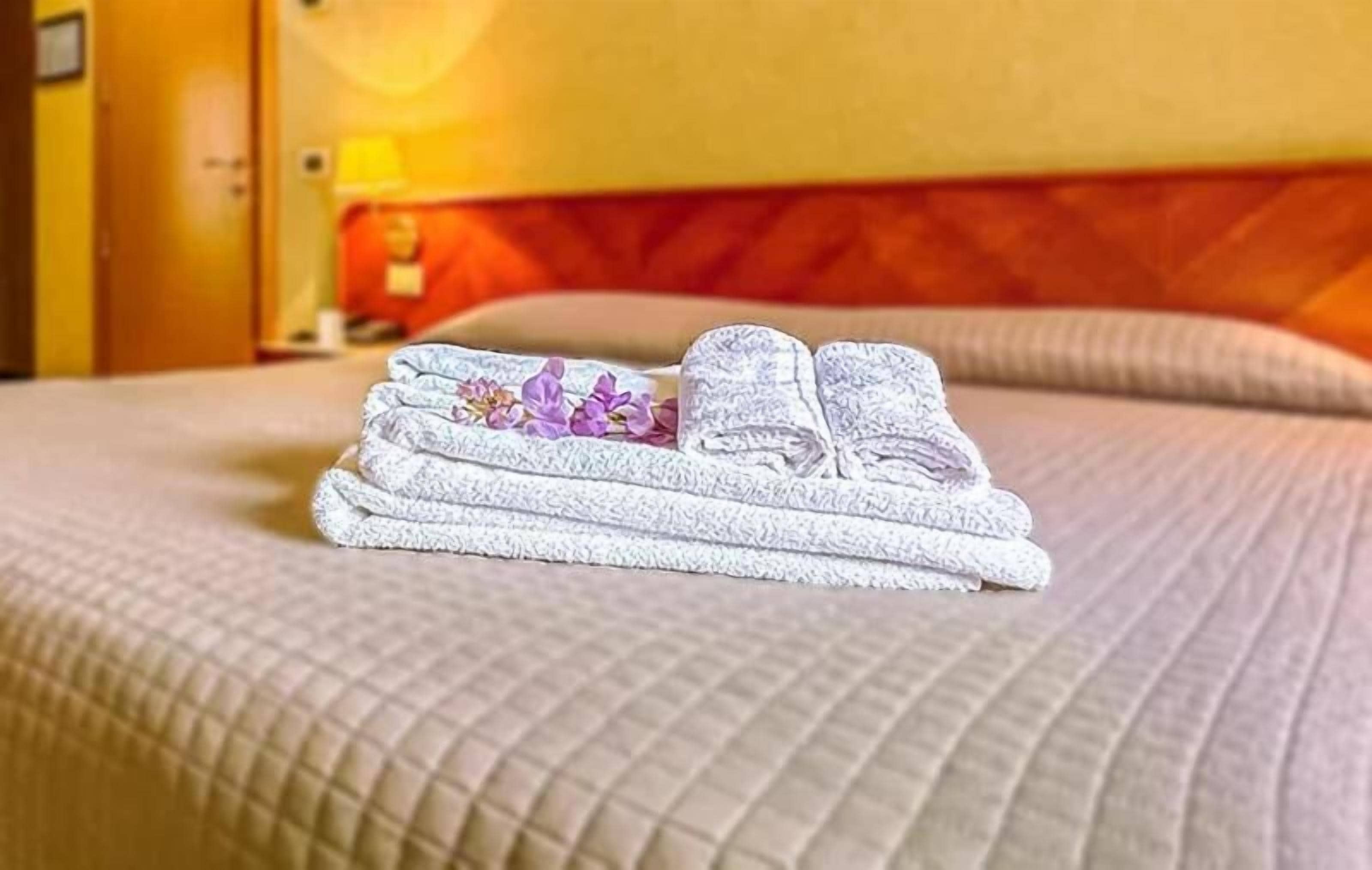 Una toalla doblada con un estampado floral sobre una cama en una habitación de hotel.