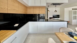 A modern kitchen with white cabinetry, a black countertop, and wooden accents. - Vilamoura Deluxe 2 With Pool by Homing (Loulé)