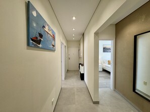 A hallway with artwork, a door, and a bed in the background. - Vilamoura Deluxe 2 With Pool by Homing (Loulé)