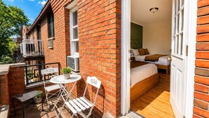 A brick exterior with a balcony, a small table, and two chairs.