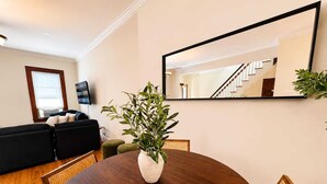 A modern living room with a round dining table, a sofa, a TV, and a staircase.