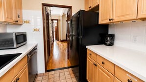 A kitchen with wooden cabinets, a black refrigerator, a microwave, and a coffee maker.