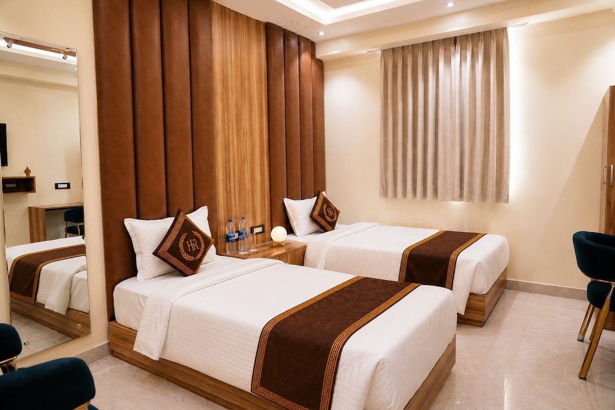A hotel room with two beds, a mirror, a desk, and a chair.