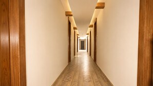 A long, narrow hallway with wooden walls and a patterned floor, leading to a door at the end. - Royal  Chandra Hotels (Patna)