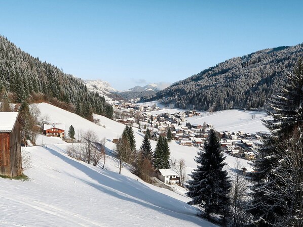 Un villaggio innevato con edifici e alberi, circondato da montagne.