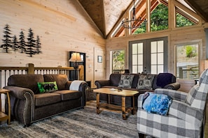 A cozy cabin interior with a wooden interior, a sofa set, a coffee table, and a fireplace. - Tennessee Sunrise | Mountain Views, 3 King Suites, WifFi & Games (Sevierville)