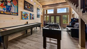 A room with a foosball table, a pool table, and a billiards table. There are large windows and a wooden ceiling. - Tennessee Sunrise | Mountain Views, 3 King Suites, WifFi & Games (Sevierville)