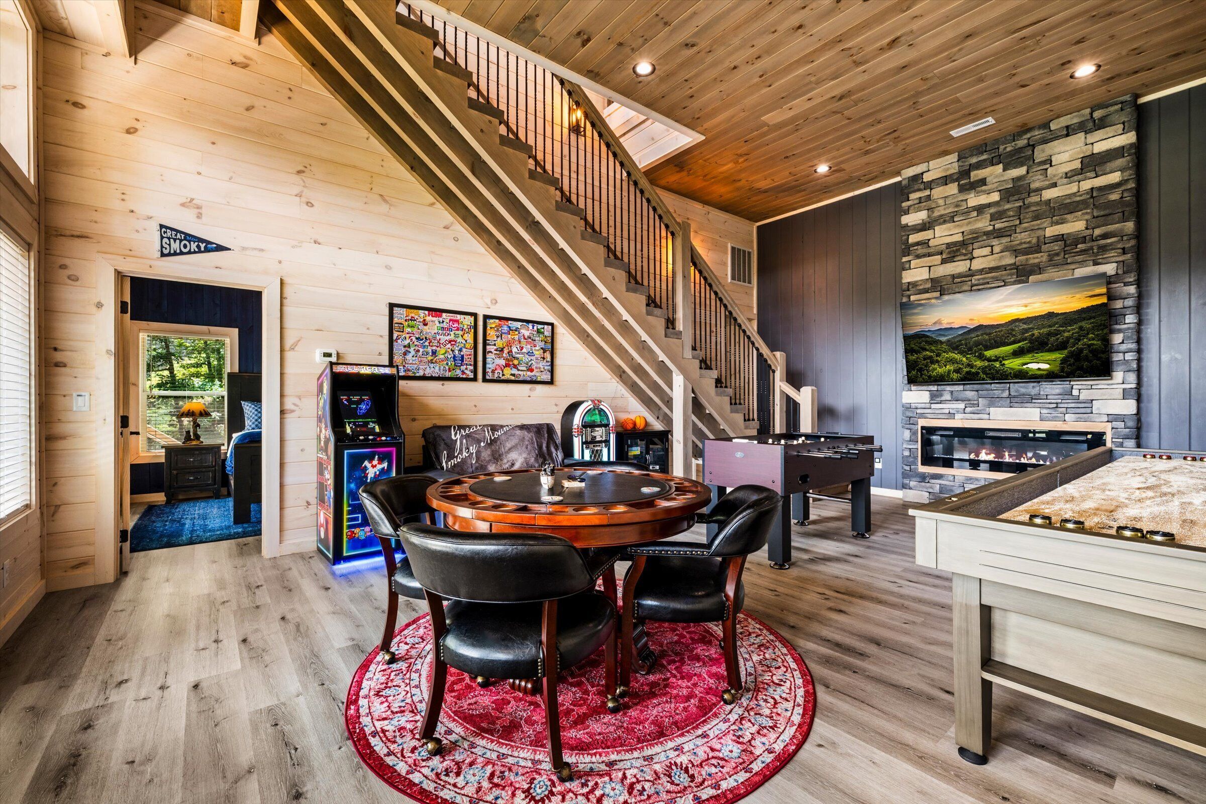 Une pièce spacieuse avec un escalier en bois, une table de billard, une table de baby-foot et une cheminée.
