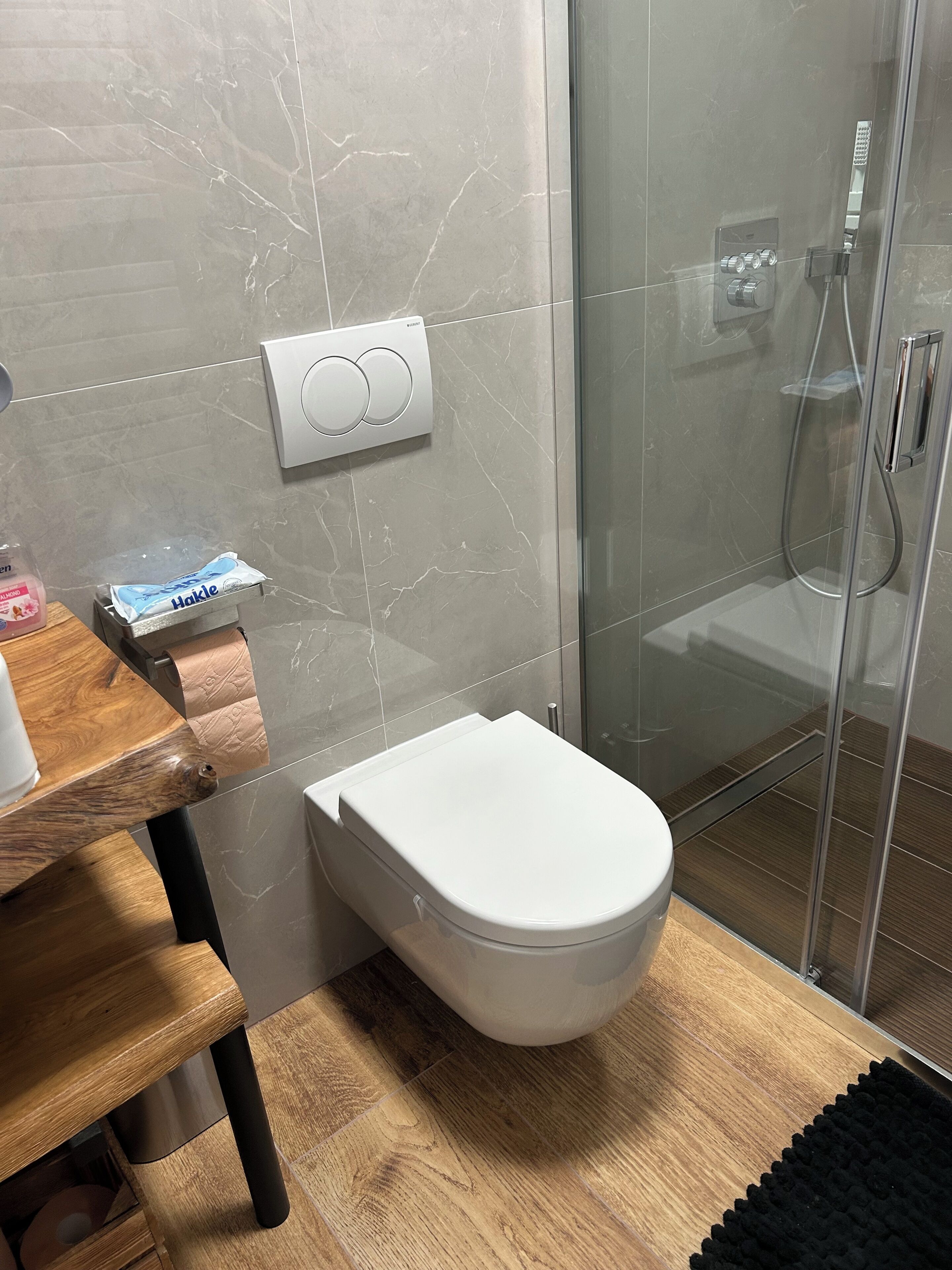 A bathroom with a toilet, a shower enclosure, and a towel rack.