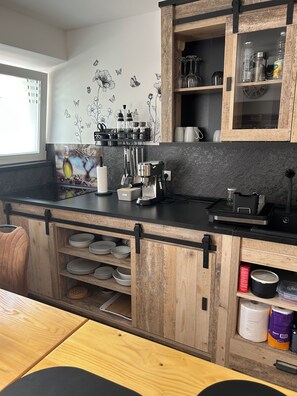 A kitchen with wooden cabinets, a black countertop, and a window. - Ljubica House (Vodice)