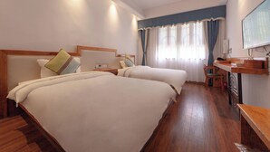 Habitación de hotel con dos camas, un escritorio, una silla y un televisor.