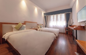 Quarto de hotel com duas camas, uma escrivaninha, uma cadeira e uma televisão.