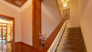 Una escalera de madera con un jarrón de flores en la barandilla.