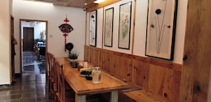 A wooden dining table with chairs, a potted plant, and a decorative wall hanging.