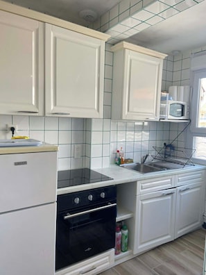 A kitchen with white cabinets, a microwave, a sink, and a stove. - Le Bruit des Vagues, an apartment 50 meters from the ocean (Quend)