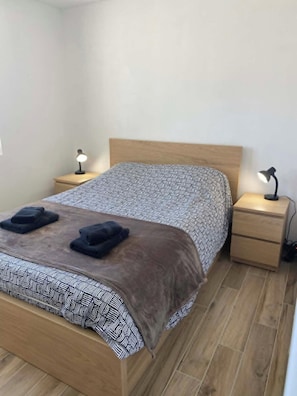 A bedroom with a bed, two bedside tables, and two lamps. - Le Bruit des Vagues, an apartment 50 meters from the ocean (Quend)