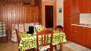 A dining area with a table covered in a floral tablecloth, wooden chairs, and a sofa with a floral-patterned cover. - Terra di Mare: Three-room apartment (sub5) with a large garden, 2 km from the sea (Vignacastrisi)