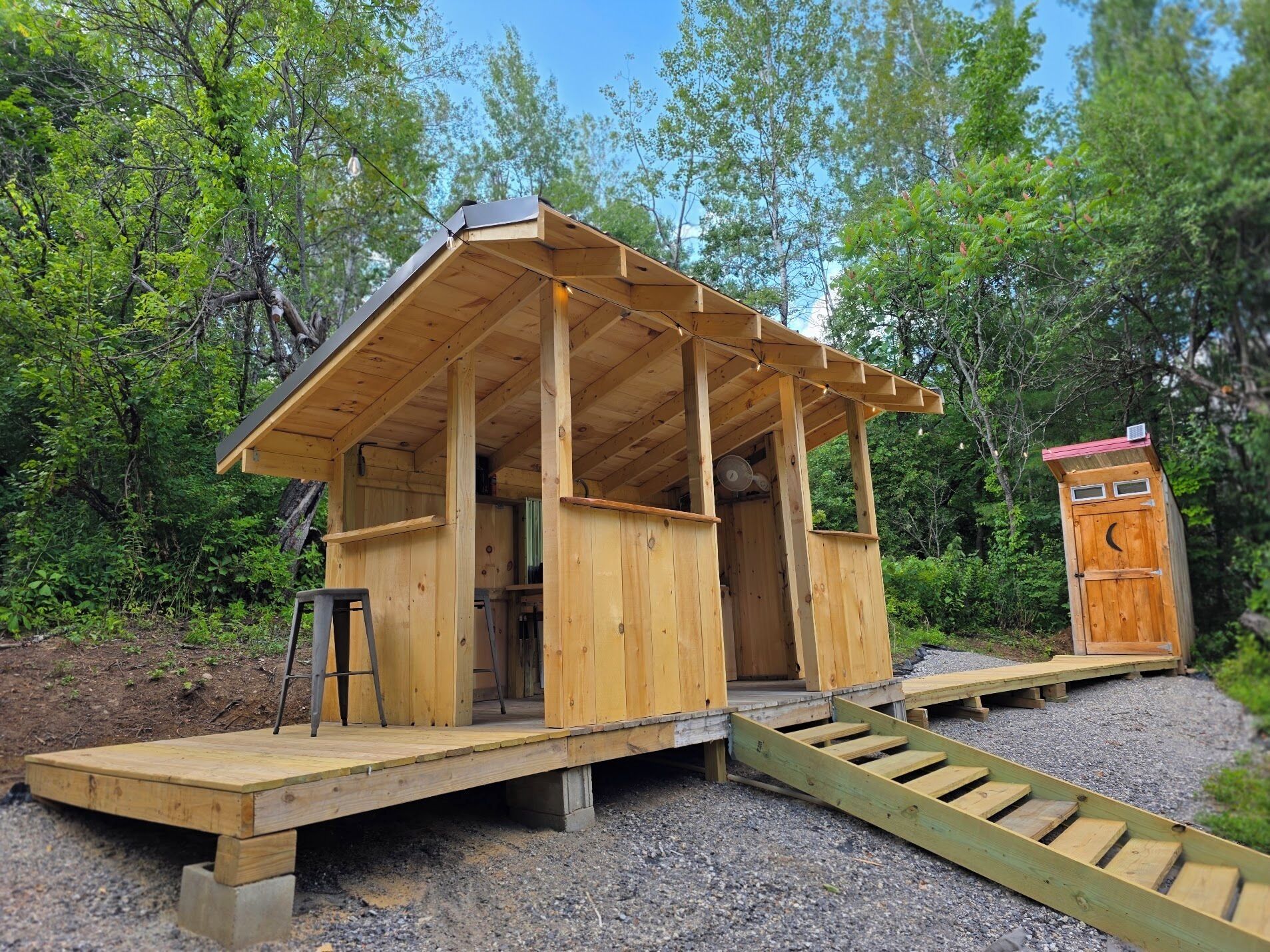 A wooden structure with a porch, a door, and a ramp leading to a platform.