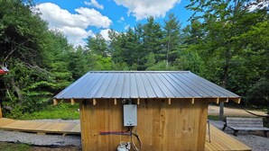 Une petite cabane en bois avec un toit en métal, un chauffe-eau et une terrasse en bois.