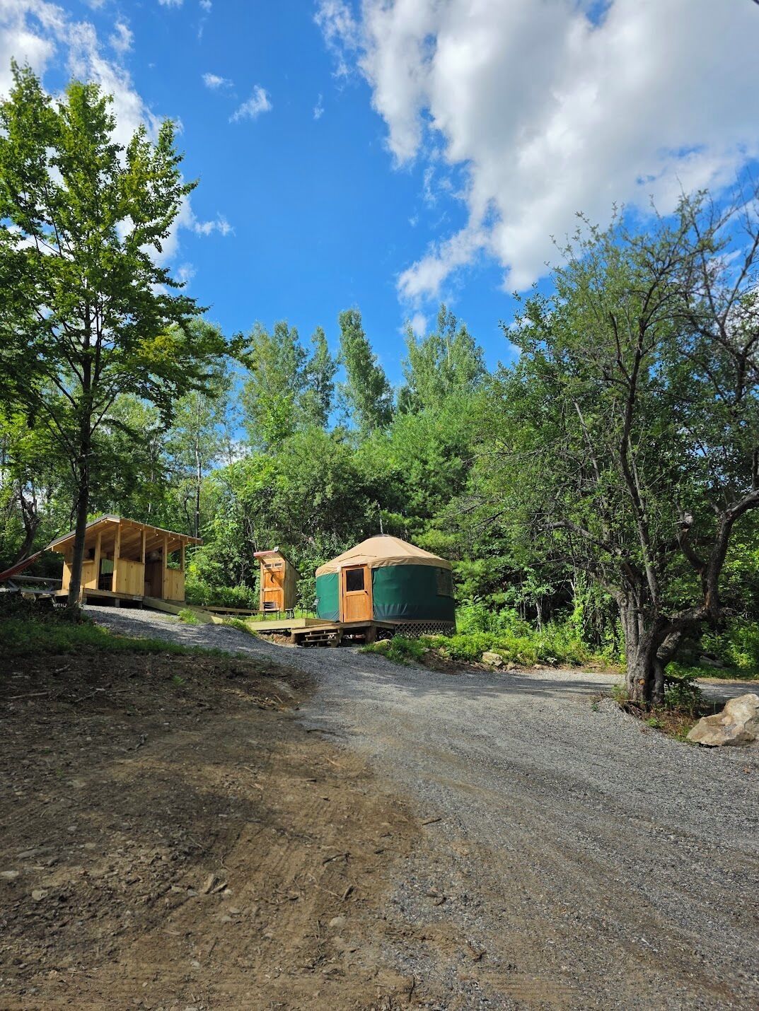 A rustic cabin with a dirt path leading to it, surrounded by trees and a clear sky.