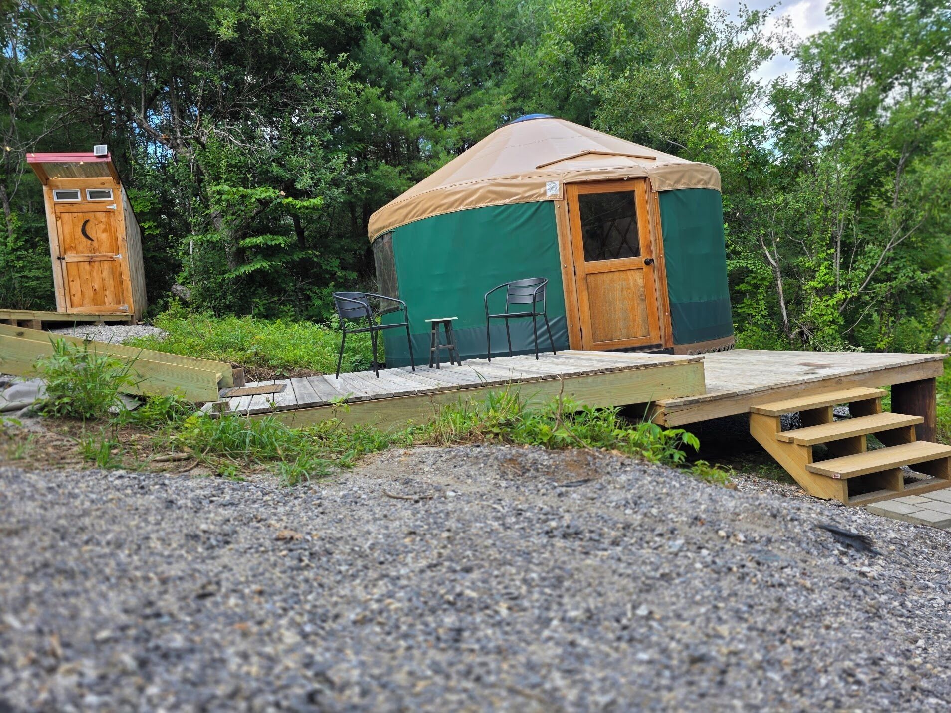 A single-room yurt with a door and a small porch area with two chairs and a table.