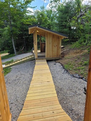 Eine Holzhütte mit überdachter Veranda und einem Kiesweg davor.