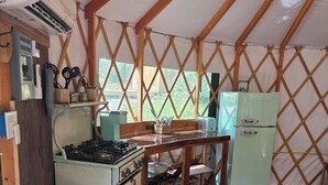 Une cuisine de taille réduite, équipée d’une cuisinière, d’un réfrigérateur et d’une petite table à manger.